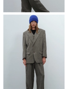 Detail of gray oversized wool blazer suit paired with a vibrant blue knit beanie hat