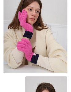 Detail of pink knitted wool gloves with navy ribbed cuffs and a small brand label