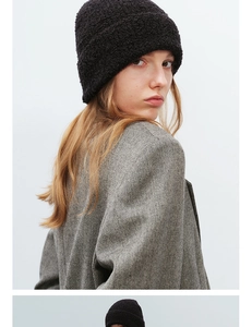 Detail shot of black boucle knit beanie featuring cozy textured wool and rolled cuff design