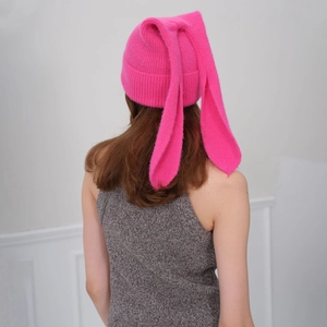 Bright pink knitted beanie with long bunny ears shown from a back view on a model