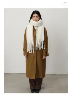 Detail of white fluffy winter scarf featuring contrast brown stitching and long tassels