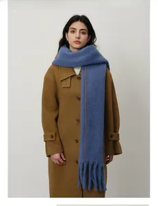 Detail of royal blue scarf with orange stitching and fringe on brown coat
