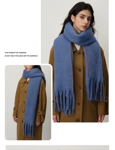 Detailed view of blue cashmere-like scarf with contrast orange stitching and long tassels