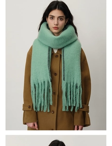Detail of mint green thick cashmere-like scarf with black zigzag embroidery and tassels