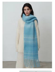 Detailed texture of thick blue plaid scarf with soft fringes on a white sweater