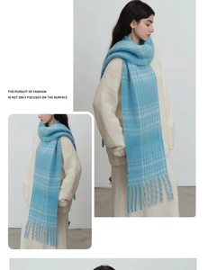Detail of light blue plaid knit scarf with long tassels on a white sweater