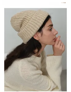 Close-up detail of beige ribbed knit beanie featuring thick wool blend yarn texture