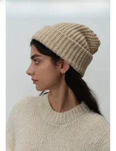 Close-up of beige wool blend knitted beanie showing thick textured ribbing and rolled cuff