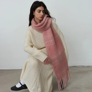 Pink plaid winter scarf with fringe details worn with a cozy white knit dress
