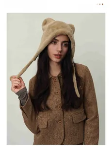 Close-up of soft brown faux fur earflap hat with cute bear ears and fuzzy pompoms