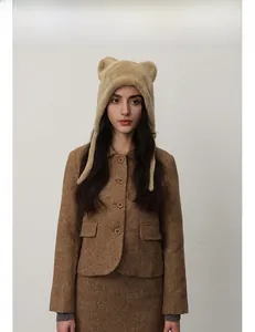 Detailed close-up of brown plush earmuff hat with cute bear ears and tweed suit fabric texture