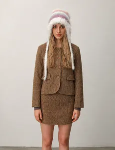 Detail showing woman in brown tweed jacket and skirt with colorful plush earflap hat