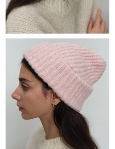 Detail of pink knitted wool beanie featuring thick texture and wide cuff design