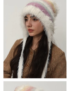 Detail of colorful rainbow gradient knit hat with white faux fur trim and long earflaps