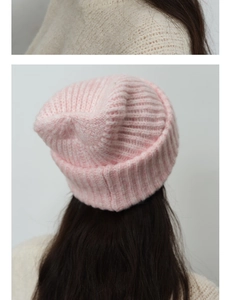 Detail of pink knitted wool beanie featuring chunky rib-knit texture and folded cuff style
