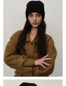 Detail shot of a premium black wool blend knit beanie styled with a camel winter coat