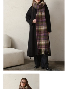 Detail of plaid mohair scarf with tassels paired with a long black woolen coat