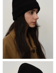 Close-up of black ribbed knit beanie made of soft wool blend styled with brown wool coat