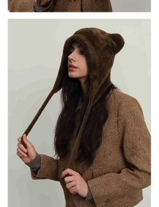 Detail of cute dark brown fuzzy cat ear beanie paired with a classic wool coat