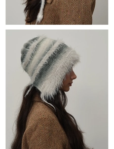 Detail of winter knit earflap hat with gray gradient stripes and plush faux fur trim