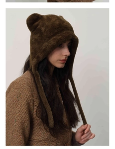 Detail of dark brown faux fur winter hat with cute ears and long straps on a model