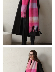 Detail of pink plaid thick scarf with tassels worn over a black wool coat