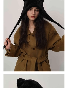 Detailed view of a plush black cat ear beanie paired with a dark brown wool coat