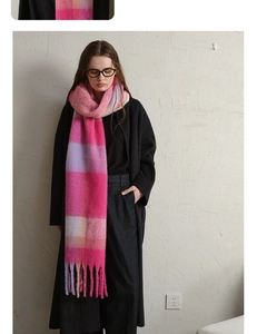 Detail of pink and purple plaid scarf with thick tassels styled on a black coat