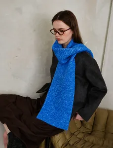 Close-up of blue knit scarf showing ribbed diamond texture and soft winter wool blend