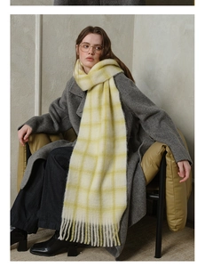 Detail shot of soft wool scarf showing large yellow and beige plaid pattern with tassels