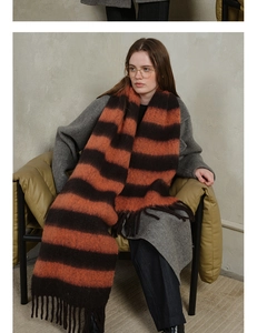 Close-up of thick striped knit scarf in orange and chocolate brown with tassels