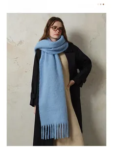 Close-up of sky blue thick knit wool blend scarf with long fringe on a female model