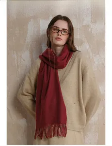Close-up of burgundy wool scarf fringe detail with soft texture on a beige background