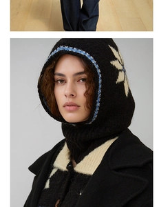 Macro detail of black wool balaclava featuring knit snowflake pattern and blue edge trim
