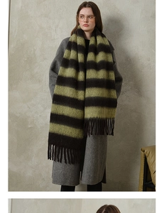 Close-up of thick green and black striped knit scarf with long tassels on a model