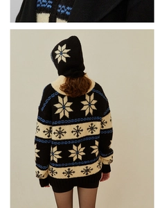 Detail of wool knit balaclava with white snowflake pattern and blue stripes on black base