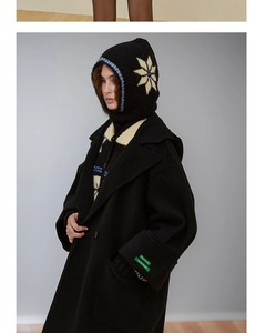 Detail of wool balaclava with snowflake pattern paired with a black wool blend overcoat