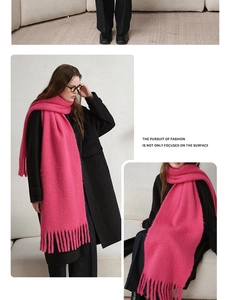 Detail of soft pink wool blend scarf with fringe tassels worn over a black coat