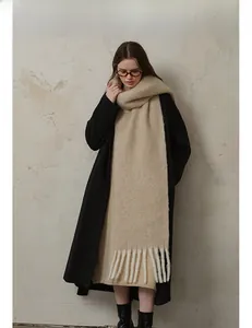 Close-up of beige thick wool knit scarf with soft fringe tassels and plush texture
