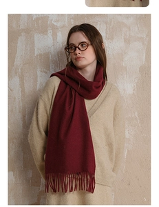 Close-up of deep red wool scarf fringe detail on model in warm beige sweater