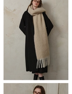 Close-up of thick beige wool scarf featuring long fringe tassels and soft knit texture