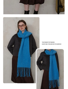 Detail of blue wool-blend boucle scarf with long tassels and thick knitted texture