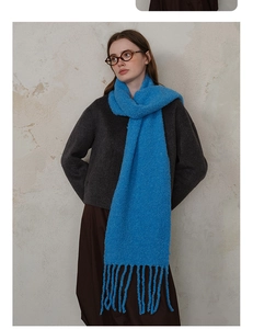 Detailed texture of bright blue wool-blend scarf with soft boucle knit and long tassels