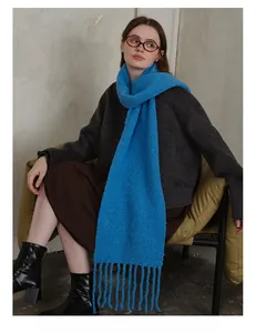 Detailed texture of bright blue wool blend knit scarf featuring soft fringe tassels