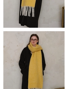 Close-up of thick bright yellow wool scarf with cream tassels on black wool coat