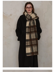 Close-up of thick plaid scarf featuring green and beige wool blend texture with stitched edges