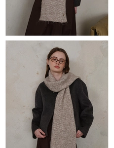 Close-up of knit scarf with herringbone pattern and metallic logo detail in oatmeal color