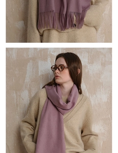 Close-up of purple knit wool scarf with fringe detailing on a beige sweater