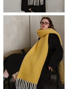 Close-up of bright yellow thick knit wool scarf with black and white fringe tassels