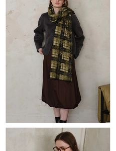 Detail view of olive green and black plaid scarf with textured hem and cozy wool-like finish
